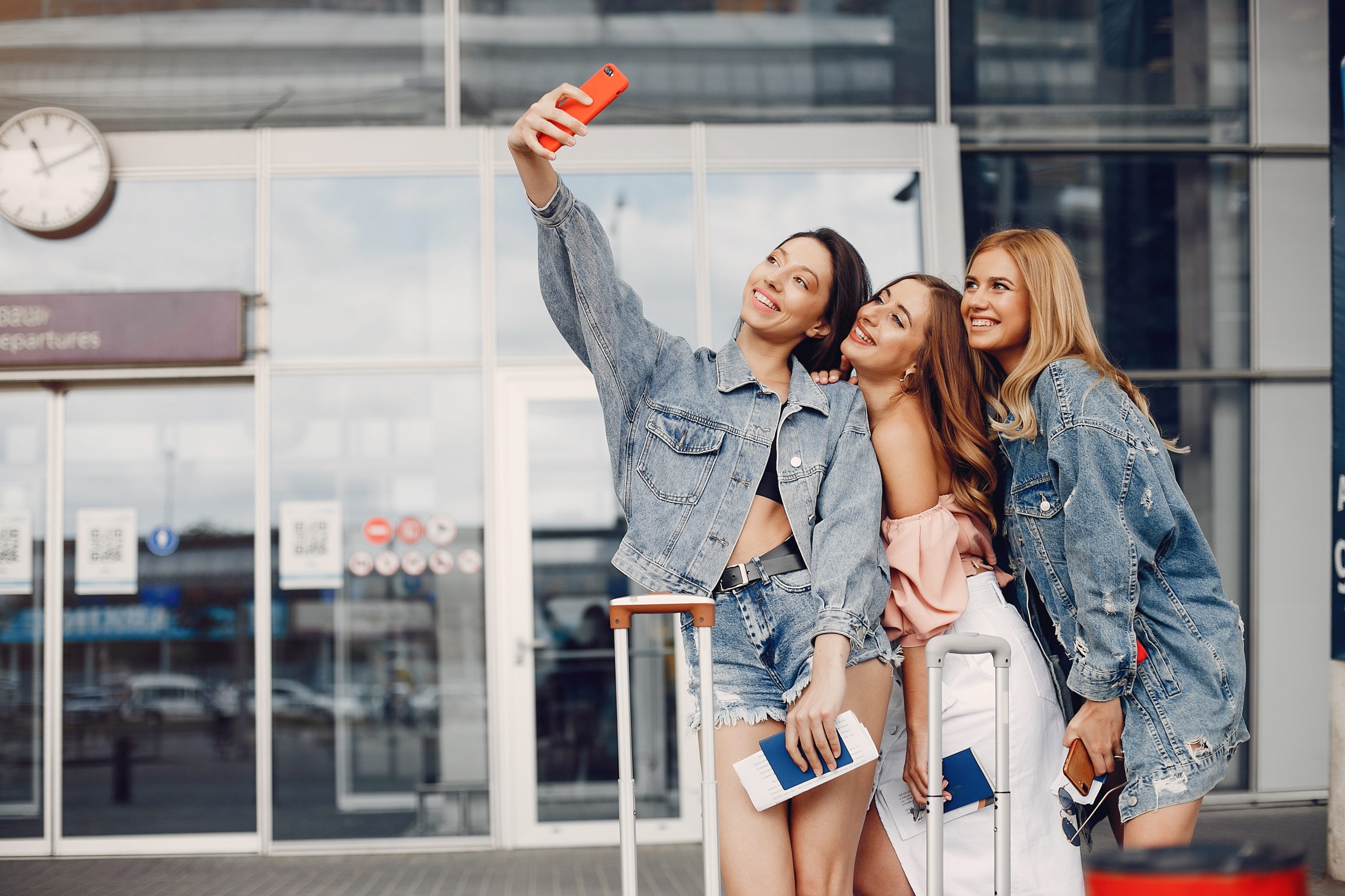 friends taking selfies at the airport before flight